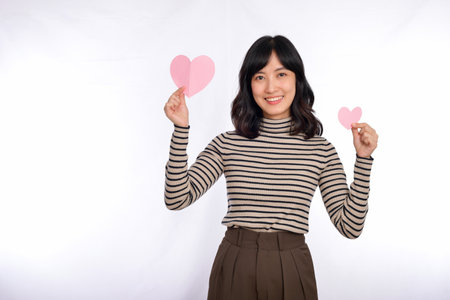 Young asian woman holding pink paper hearts isolated on white background.の写真素材