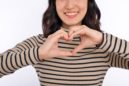 Young asian woman hands making a heart shape on white isolated background