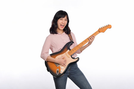 Asian woman playing a vintage sunburst electric guitar isolated on white background.の写真素材