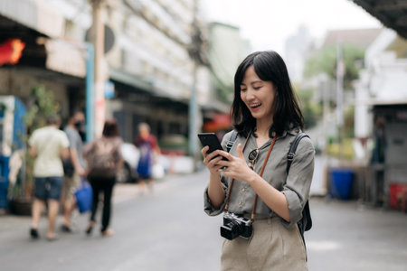 Young Asian woman backpack traveler using mobile phone, enjoying street cultural local place.の写真素材