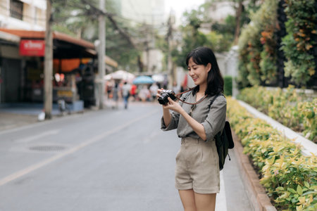 Young Asian woman backpack traveler using digital compact camera, enjoying street cultural local place and smile.の写真素材