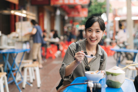 Happy young Asian woman backpack traveler enjoying street food at China town street food market in Bangkok, Thailand.の写真素材