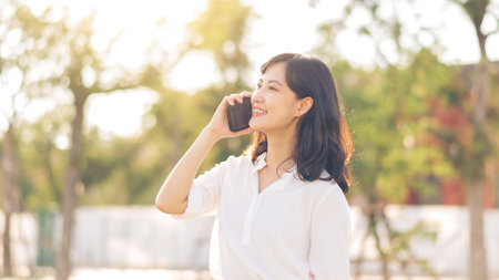 Portrait beautiful young asian woman with smart mobile phone around outdoor nature view in sunny summer dayの写真素材