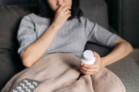 Asian woman with cold and flu reading instructions on a medicine bottleの写真素材