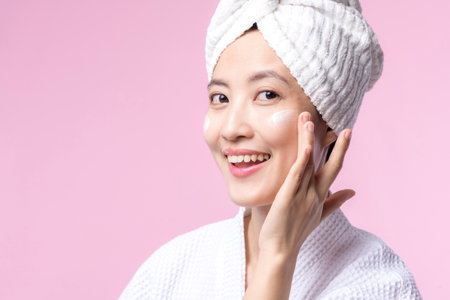 Asian young woman applying facial skincare face cream, cosmetic moisturiser on healthy natural skin make up face. Portrait glowing smile girl person model with care beauty product, spa, cosmetology.の写真素材