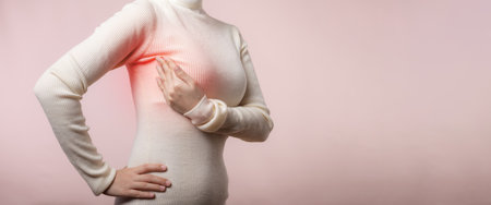 Woman hands checking lumps on her breast for signs of breast cancer on pink background. Healthcare concept.の写真素材