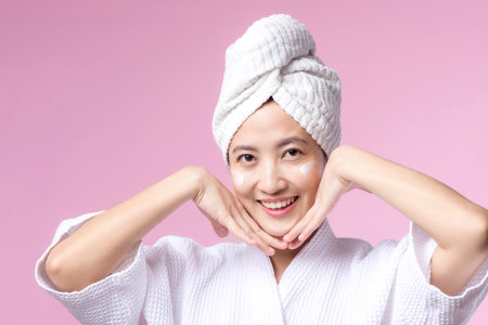Asian young woman applying facial skincare face cream, cosmetic moisturiser on healthy natural skin make up face. Portrait glowing smile girl person model with care beauty product, spa, cosmetology.の写真素材