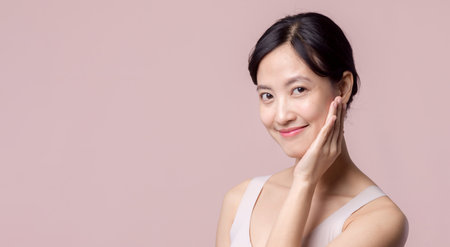 Young beautiful asian woman happy smile with clean face skin in brown bra, spa suit on pink background. Skincare, treatment, wellness therapy, facial care, beauty female health, cosmetology conceptの写真素材