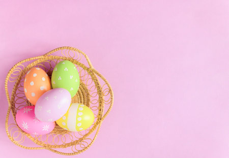 Happy Easter holiday greeting card concept. Colorful Easter Eggs and spring flowers on pastel pink...