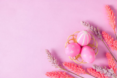 Happy Easter holiday greeting card concept. Colorful Easter Eggs and spring flowers on pastel pink background. Top view, flat lay, copy space.の写真素材
