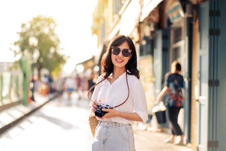 Portrait of young beautiful woman with camera explore street in Bangkok, Thailandの写真素材