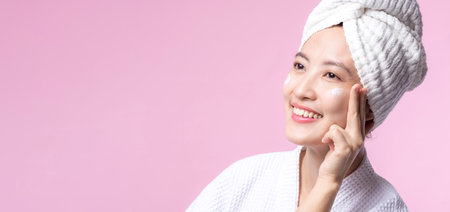Asian young woman applying facial skincare face cream, cosmetic moisturiser on healthy natural skin make up face. Portrait glowing smile girl person model with care beauty product, spa, cosmetology.の写真素材