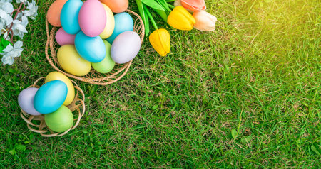 Happy Easter holiday greeting card concept. Colorful Easter Eggs and spring flowers on green grasses...