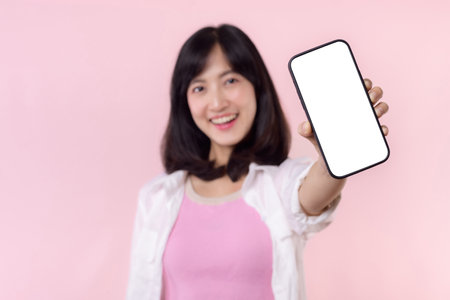 happy smiling asian young woman recommending showing new application or mobile advertisement, mockup smartphone template banner isolated on pink background. Collage blank screen digital mobile device.の写真素材