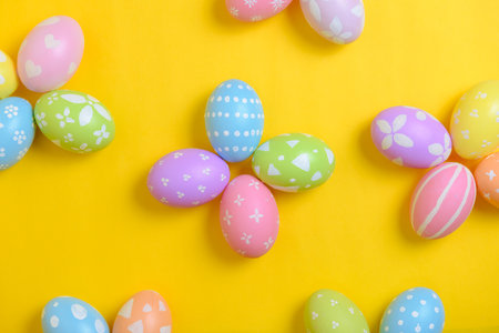 Happy easter holiday celebration concept. Group of painted colourful eggs decoration on a yellow background. Seasonal religion tradition design. Top view, copy space, flat lay.の写真素材