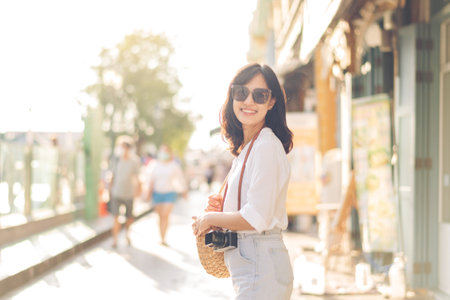 Portrait of young beautiful woman with camera explore street in Bangkok, Thailandの写真素材