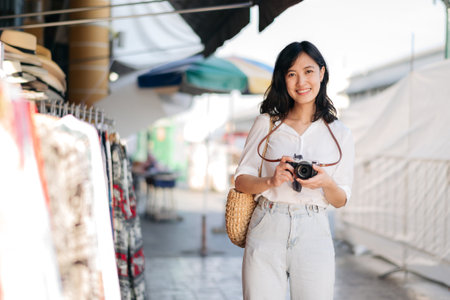 Portrait of young beautiful woman with camera explore street in Bangkok, Thailand