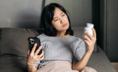 Sick asian woman with medicine having video call conference medical app in telehealth on mobile phone.の写真素材