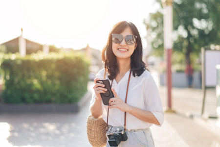 Portrait of young beautiful woman with camera explore street in Bangkok, Thailandの写真素材