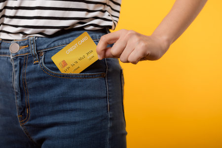 hand of person woman holding plastic credit card out of the pocket blue jean plants isolated on...