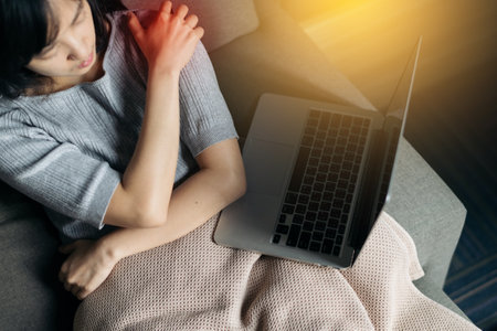 Asian woman has shoulder pain. Female holding painful shoulder with another hand. People with body-muscles problemの写真素材