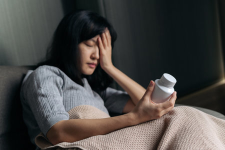 Asian woman with cold and flu reading instructions on a medicine bottleの写真素材