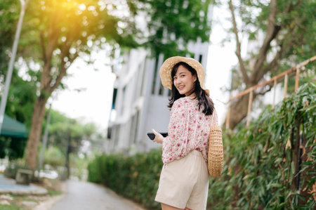 Portrait of young asian woman traveler with weaving hat and basket happy smile on green public park nature background. Journey trip lifestyle, world travel explorer or Asia summer tourism concept.の写真素材