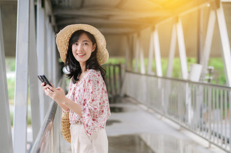 asian young woman traveler with weaving basket using mobile phone and standing on overpass. Journey...