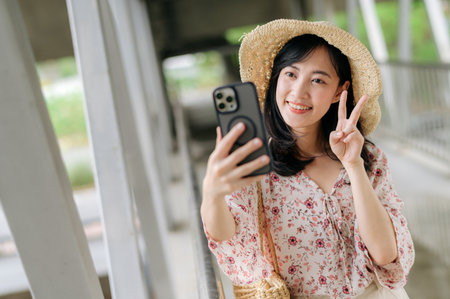 asian young woman traveler with weaving basket selfie with mobile phone and standing on overpass....