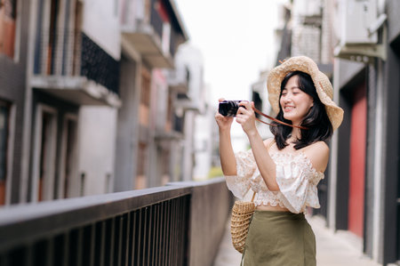 Happy asian youth woman with camera travels street city trip on leisure weekend. Young hipster female tourist sightseeing summer urban Bangkok destination. Asia summer tourism concept.の写真素材