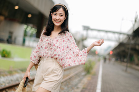 asian young woman traveler with weaving basket happy smiling looking to a camera beside train...