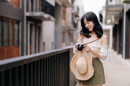 Happy asian youth woman with camera travels street city trip on leisure weekend. Young hipster...