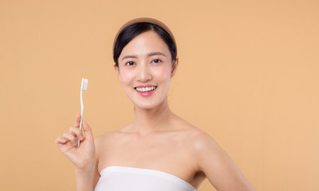 portrait young beauty woman with healthy happy smile holding toothbrush in her hand at morning isolated on beige studio background. hygiene tooth mouth clean care and dental concept.の写真素材