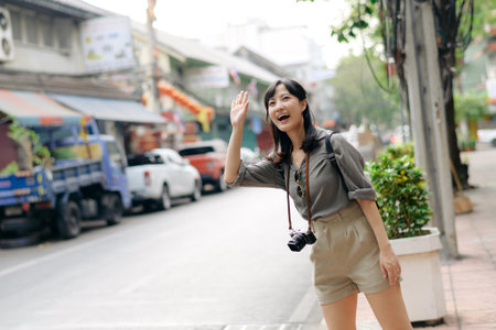 Smiling young Asian woman traveler hitchhiking on a road in the city.の写真素材