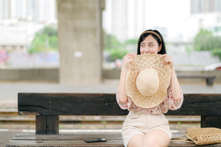 asian young woman traveler with weaving basket waiting for train in train station. Journey trip lifestyle, world travel explorer or Asia summer tourism concept.の写真素材