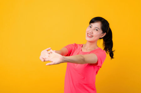 Portrait young beautiful asian sports fitness woman happy smile wearing pink sportswear posing exercise training workout isolated on yellow studio background. wellbeing and healthy lifestyle concept.の写真素材
