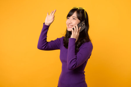 Young asian woman talking on mobile phone isolated on yellow background.の写真素材