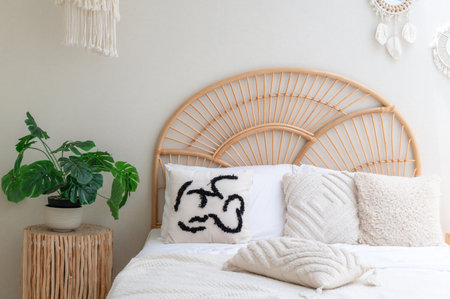 Real photo of white pillows on wooden weave bed in minimal bedroom interior with green plants.の写真素材
