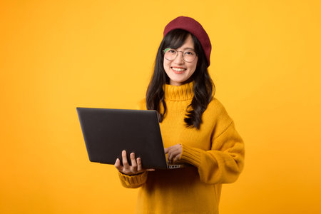 Ethnic lady working on a computer, wearing a red beret, eyeglasses, and yellow sweater, against a...