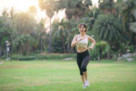 pretty asian woman jogger running in green nature public park.の写真素材