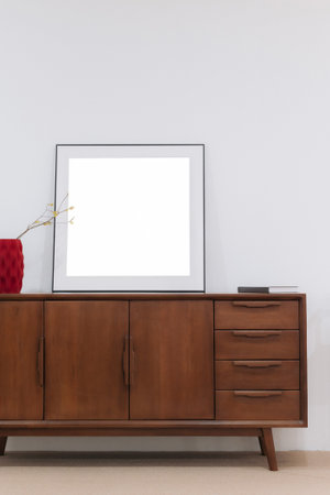 A Modern wooden sideboard with blank frame and decorative vaseの写真素材
