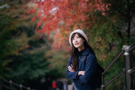 Asian woman in casual dress embraces the beauty of fall in Kyoto, enjoying holiday filled with friends, smiles, and colorful foliage by the lake. A cheerful and scenic journey.の写真素材