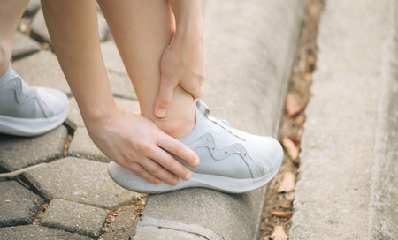 Sprained ankle problem. woman jogger. 30s asian female wearing sportswear holding her ankle with...