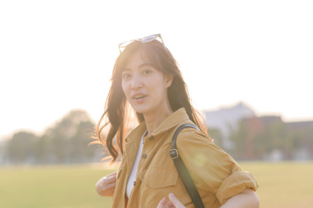 Traveler woman 30s stands bathed in the golden glow of sunset, embracing the freedom of exploration. on summer holiday weekend vacation tripの写真素材