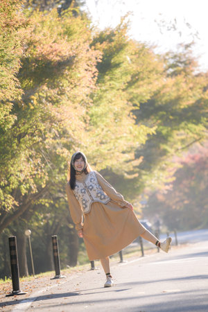 Asian woman in Kyoto's fall, wearing casual dress. Elegant portrait amid colorful maple foliage, capturing her cheerful smile and the refreshing beauty of the seasonal change.の写真素材
