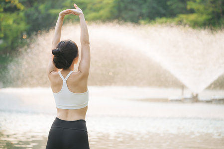 Female jogger. Fit young Asian woman with sportswear stretching muscle in park before running and enjoying a healthy outdoor. Fitness runner girl in public park. Wellness being conceptの写真素材