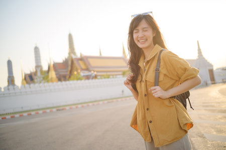 Southeast asian woman travel concept shows joyful woman smiling brightly while exploring cultural site in warm sunlight, capturing essence of travel and happinessの写真素材