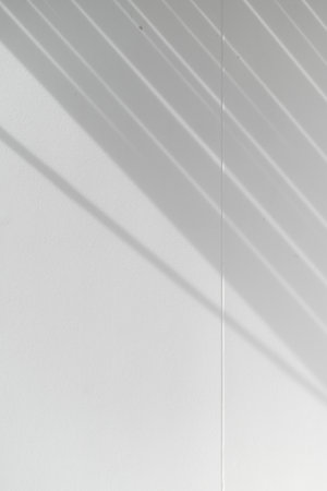 A diagonal shadow line pattern plain white wall from strong natural light creates graphic element....