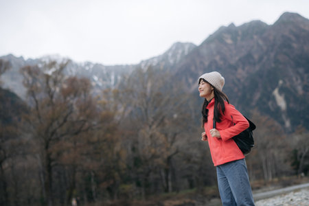 A southeast asian woman travel in nature with mountain background wearing casual outdoor clothing and backpack enjoying peaceful adventure in autumn seasonの写真素材