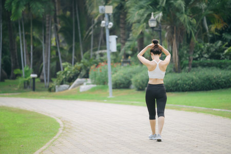 An asian woman jogger running in green nature public park, active lifestyle, fitness, outdoor exercise, healthy, peaceful moodの写真素材